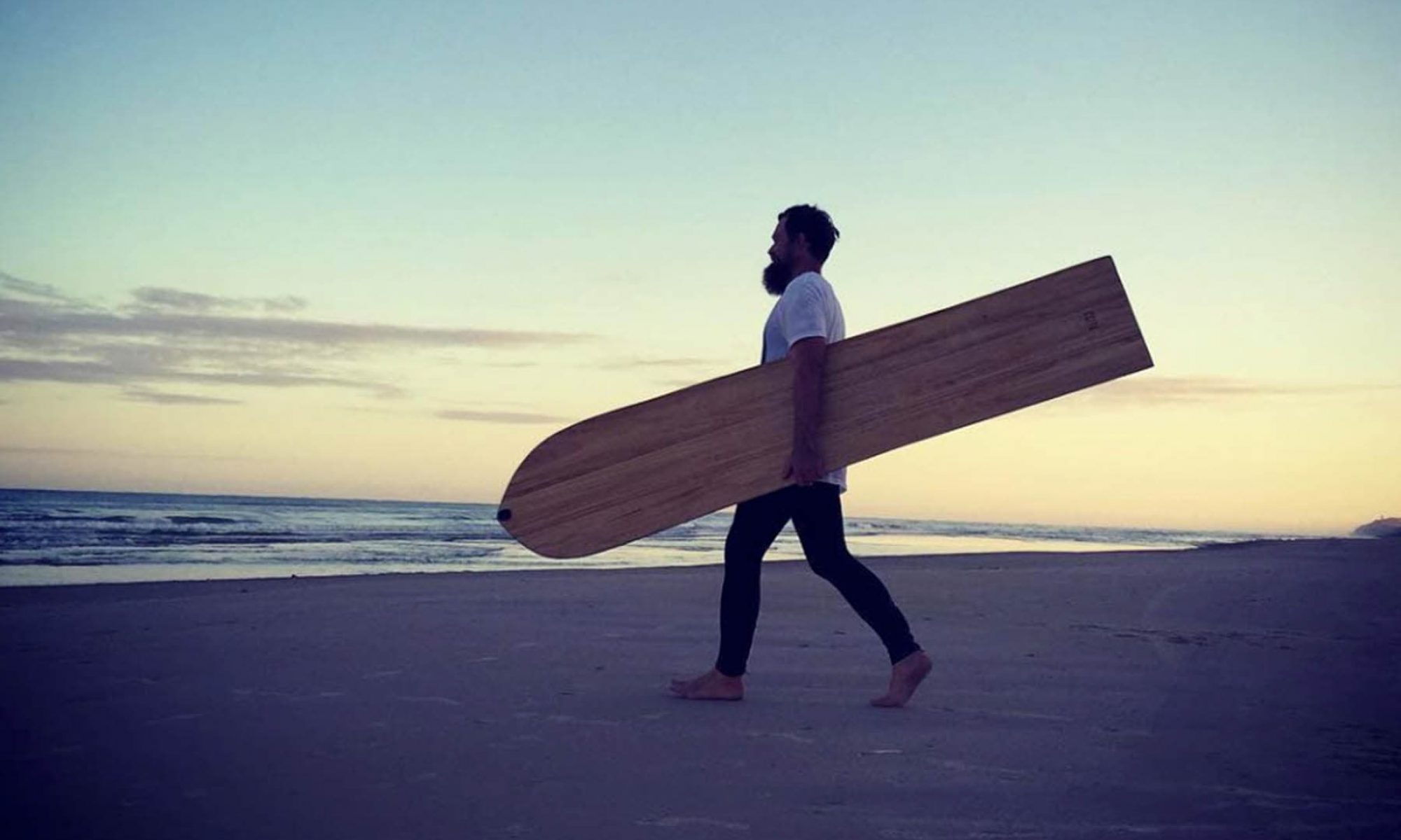 Foto: Malte Schreer mit Alaia Surfboard zum Strand bei Klitmöller